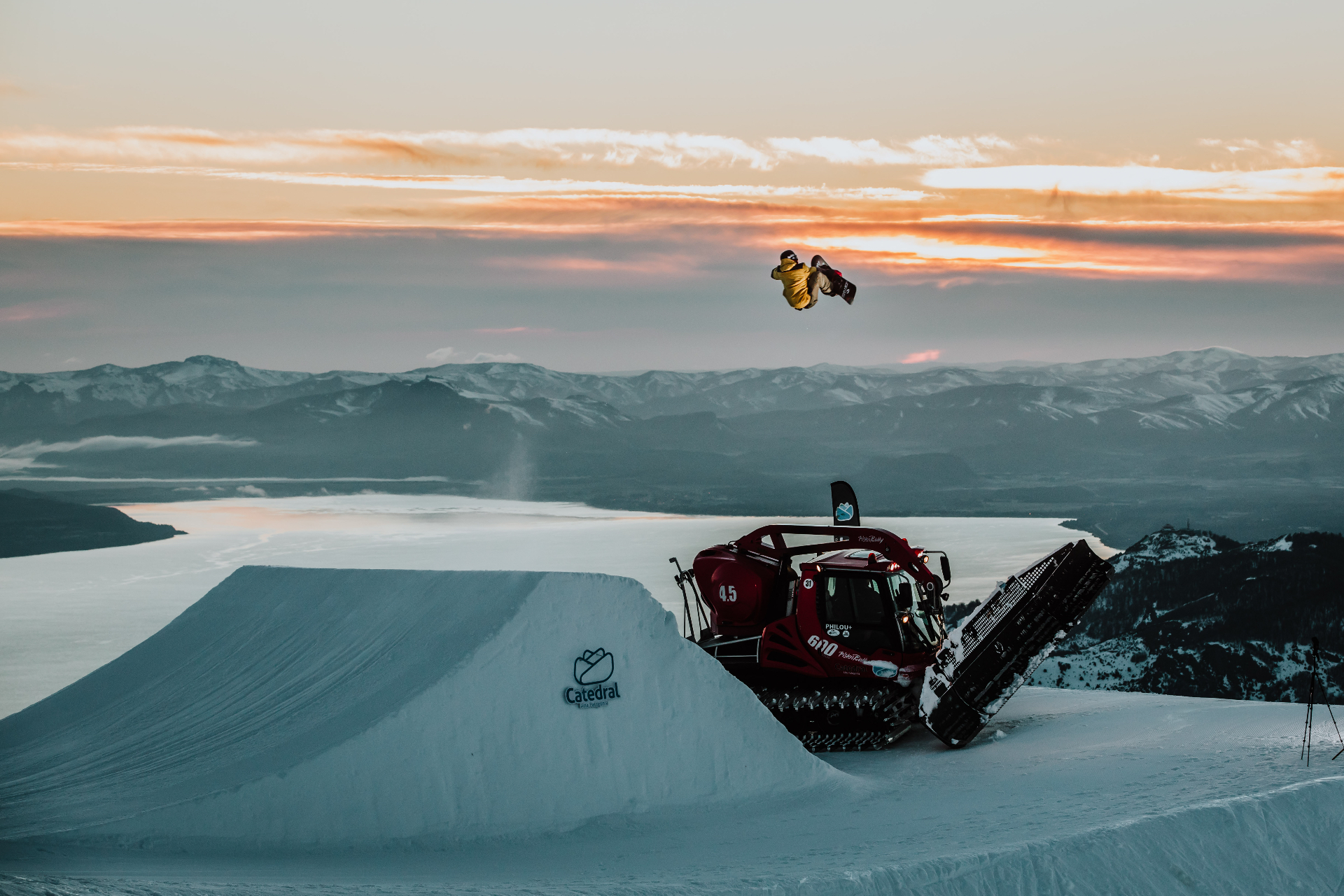 Snowboarder catching air at sunset above a Patagonian lake